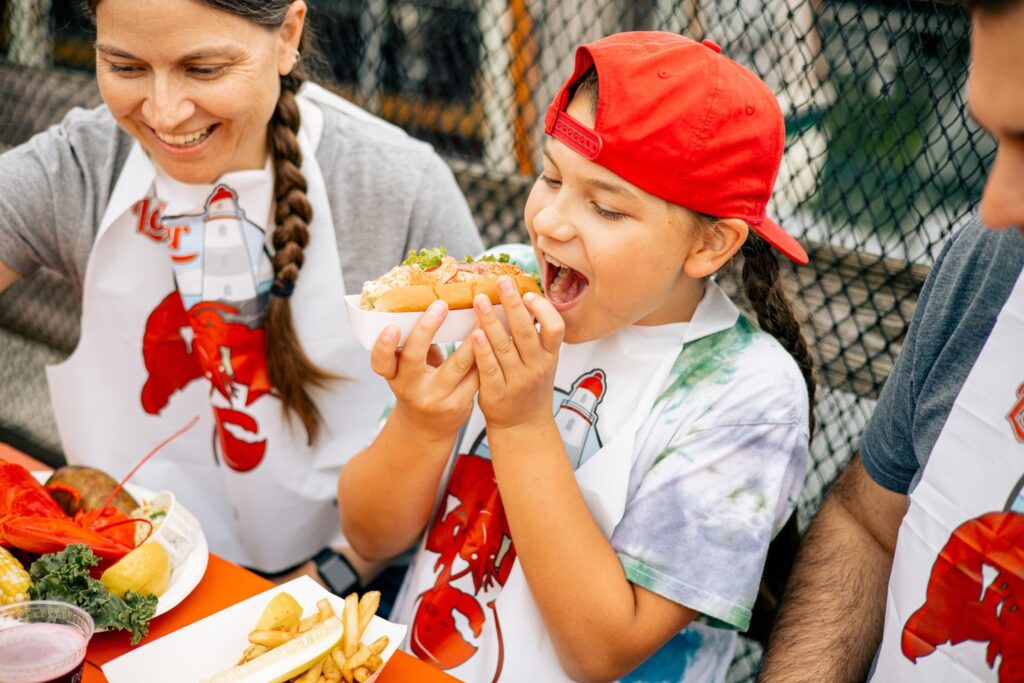 Kid eating lobster roll. Photo Credit: Jamie Mercurio Photography
