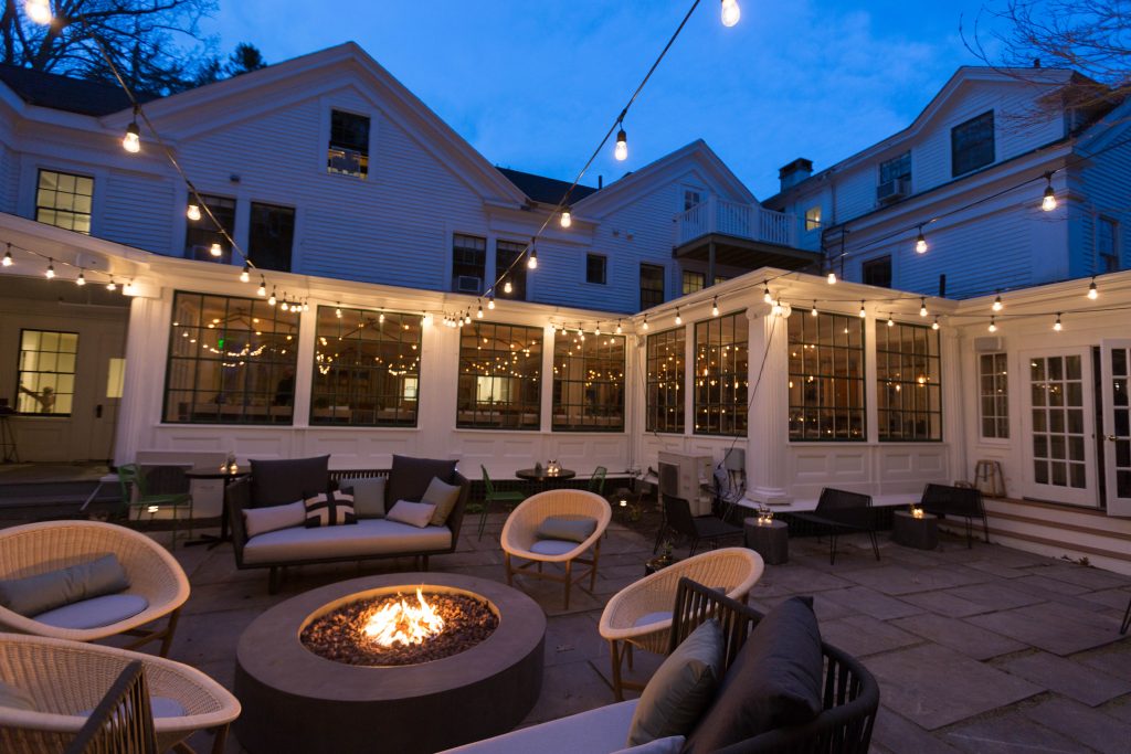 Outdoor patio with a firepit, seating, and twinkle lights at dusk. Photo Credit: Rarebrick Photography Outdoor patio with a firepit, seating, and twinkle lights at dusk. Photo Credit: Rarebrick Photography