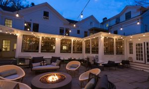 Outdoor patio with a firepit, seating, and twinkle lights at dusk. Photo Credit: Rarebrick Photography