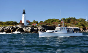 Boat cruising by Portland Head Light. Photo Provided by Casco Bay Custom Charters