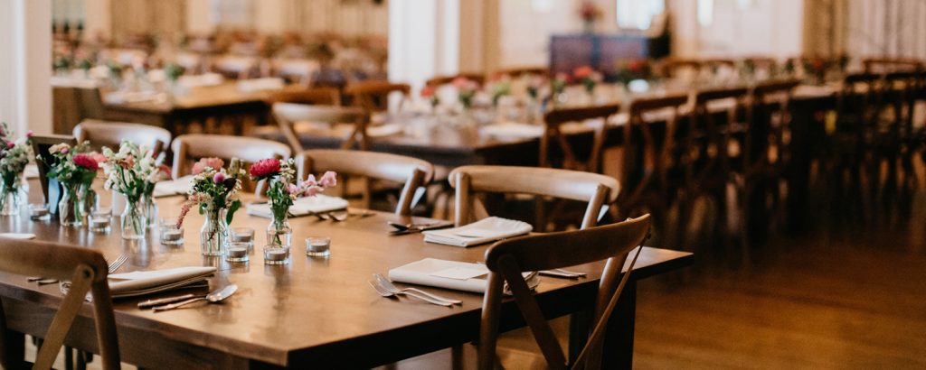 A long wooden table set for a formal event with flowers and place settings in Portland Maine.