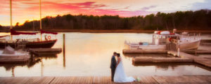 Bride and Groom Posing Together on Dock With Docked Boats Behind Them, Photo Credit: Russell Caron Wedding Photography at Nonantum Resort