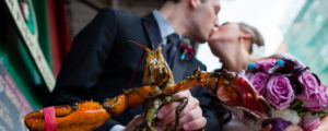 Couple Kissing with Flowers and Lobster in Front, Photo Credit: Emilie Inc
