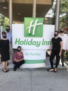 Holiday-Inn-By-the-Bay-Staff-Photo-in-Masks-with-Hibay-Sign. Photo Provided by Holiday Inn By the Bay