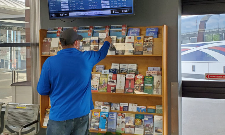 Man in Blue Reaching for Brochure at Transportation Center, Photo Credit: Visit Portland / Amy Tolk