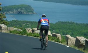 Biker overlooking water, Photo Credits: Summer Feet Cycling