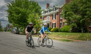Bikers with historic houses, Photo Credits: Summer Feet Cycling