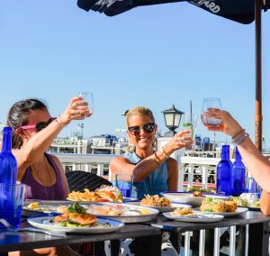 Group of people cheering drinks on deck, Photo Credits: Saltwater Grille Group of people cheering drinks on deck, Photo Credits: Saltwater Grille