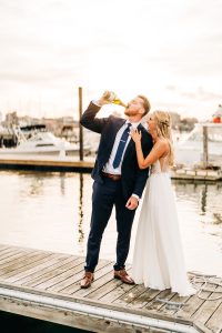 Bride and groom with champagne on the dock - photo by Radiance By Design