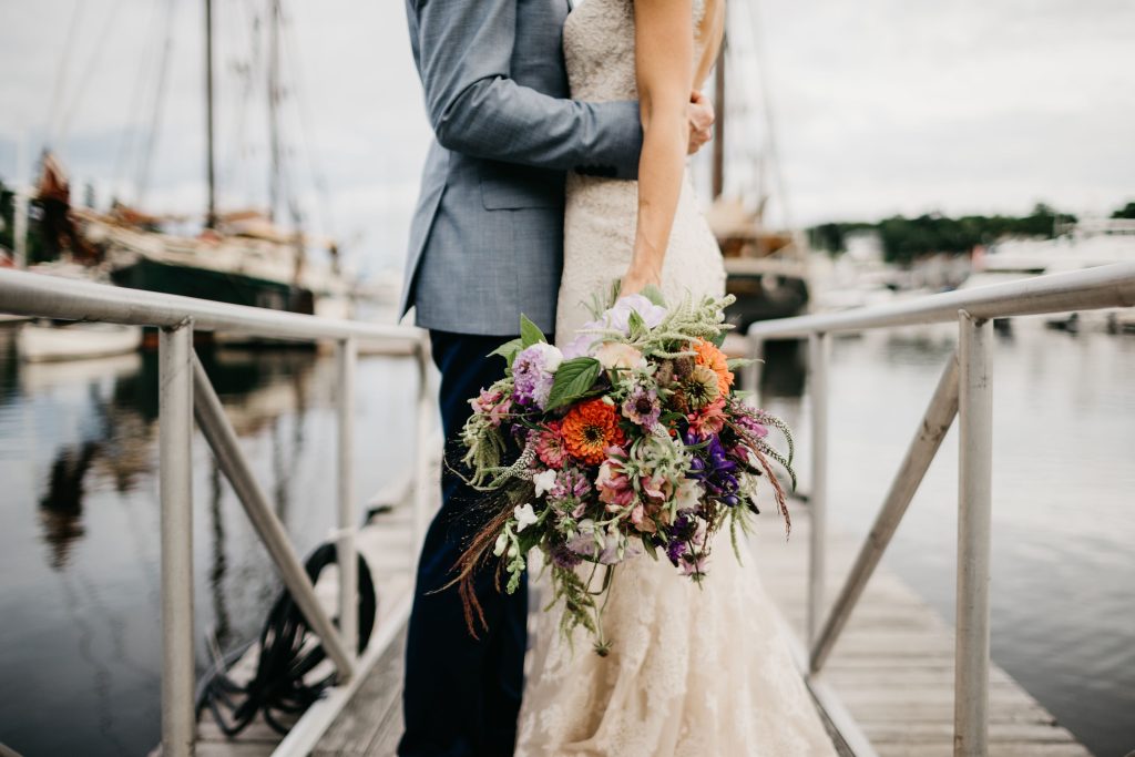 A bride and groom standing on a dock at the Camden Harbor. Photo Credit: Lindsay Vann Photography