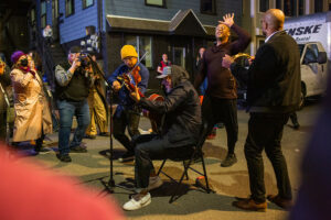 A group of people performing music on a city street at night in Portland Maine.