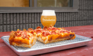 Peperoni pizza and beer on red picnic table ; Photo Credit: Peter G. Morneau Photography