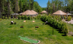 Outdoor lawn with cornhole games surrounded by yurts; Photo Credit: Peter G. Morneau Photography