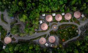Aerial of yurt community surrounded by green woods at sunset; Photo Credit: Peter G. Morneau Photography