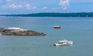 Two boats sailing past rocky island on blue water; Photo Credit: Peter G. Morneau Photography