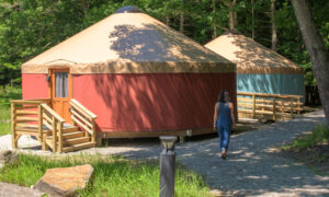 The Ecology School orange yurts with woman walking; Photo Credit: Peter G. Morneau Photography