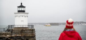 Women in Red with Maine hat near Lighthouse Photo Credit: Capshore Photography