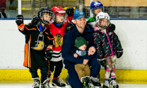 Hockey players smiling for a picture with children; Photo Credit: Maine Mariners Photography Team