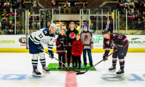 Hockey players smiling for a picture with children; Photo Credit: Maine Mariners Photography Team