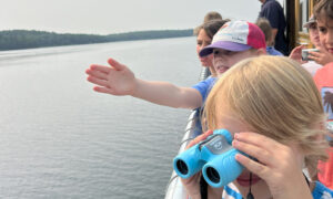Kids using blue binoculars to look at ocean; Photo Credit: Maine Maritime Museum