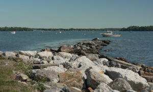 Boats sitting in the water along rocky point; Photo Credit: Digital Edge