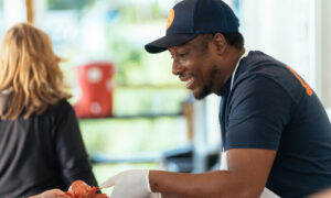 Man happily serving lobster to a person; Photo Credit: Digital Edge