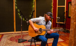 Musical artist in recording studio playing guitar; Photo Credit: Lauren Witt at Visit Portland