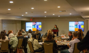 Speaker giving presentation to a room of people; Photo Credit: Lauren Witt at Visit Portland