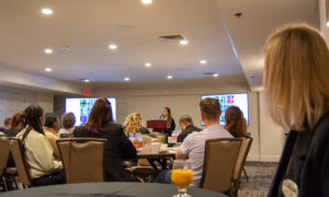 Speaker giving presentation to a room of people; Photo Credit: Lauren Witt at Visit Portland