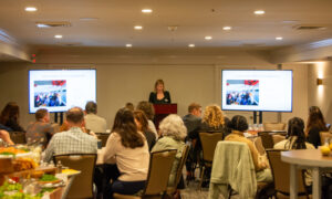 Speaker giving presentation to a room of people; Photo Credit: Lauren Witt at Visit Portland