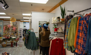 Woman trying on hat in Freeport store; Photo Credit: Lauren Witt at Visit Portland