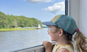 Little girl looking through window to ocean: Photo Credit: Maine Maritime Museum