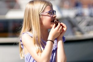Girl Eating Donut on The Portland Donut Tour. Photo Credit: Good Maine