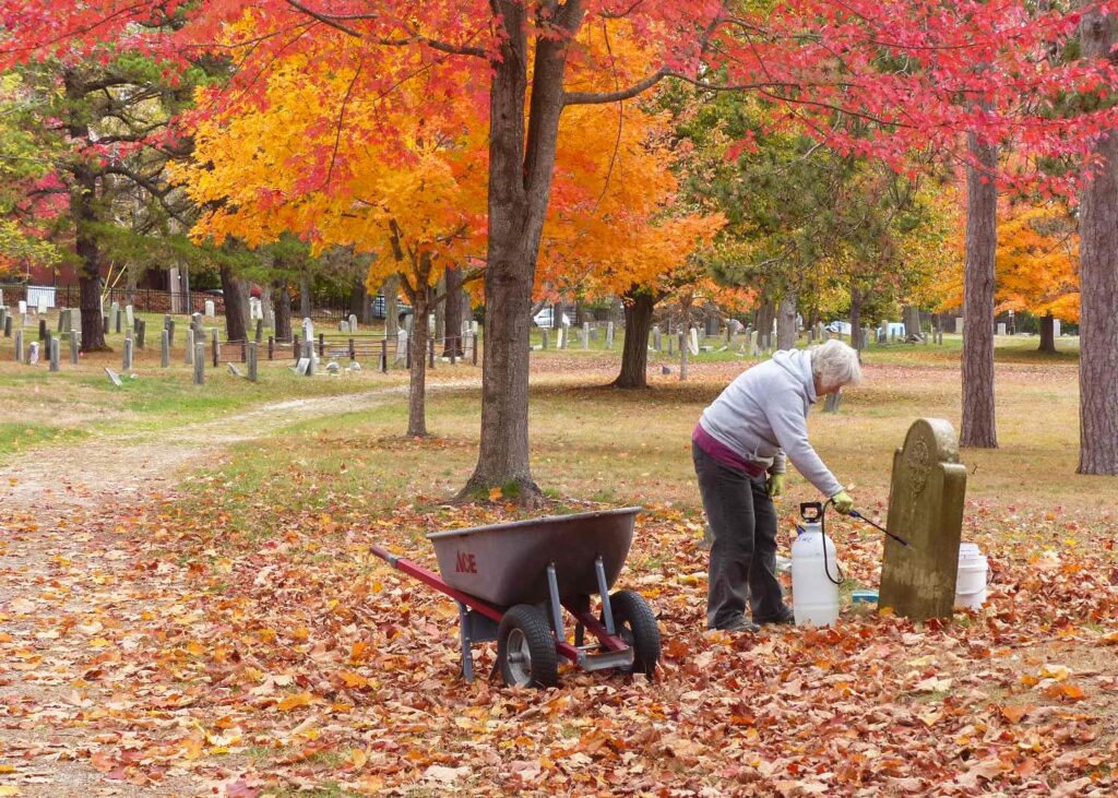 Gina Glidden cleaning headstone of Charles Parker. Photo Credit: Bill Shumaker - Stewards of the Western Cemetery