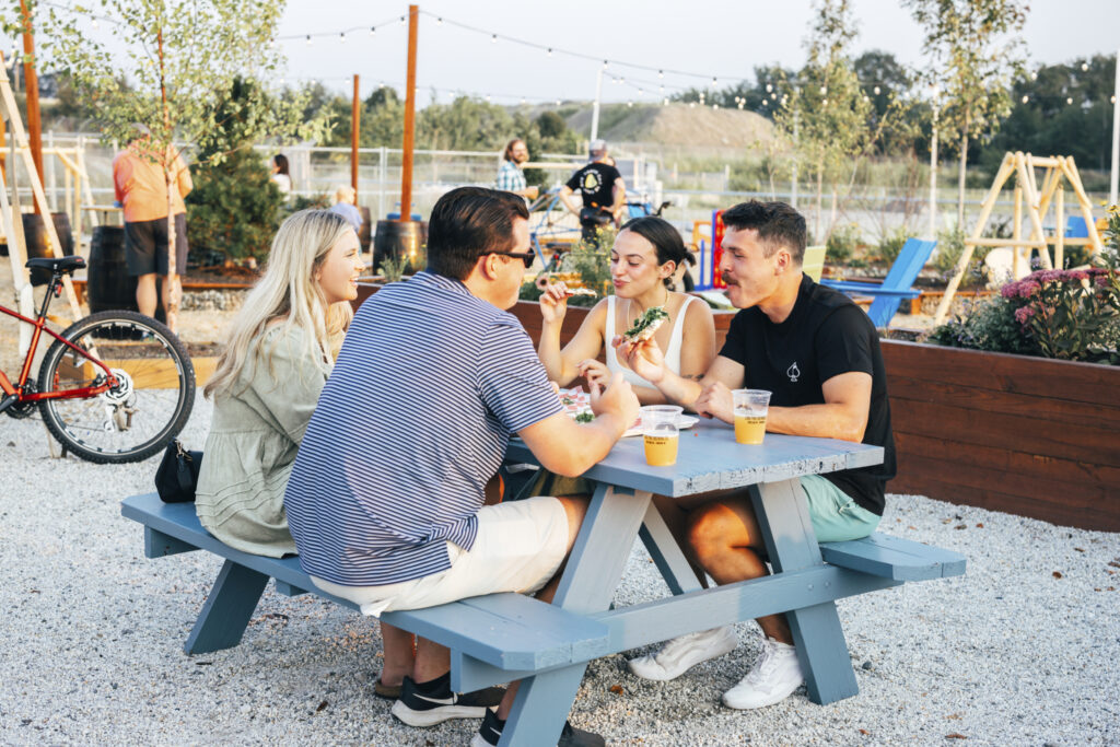 People sitting at a picnic bench at a Quarryside at Rock Row event. Photo credit: Navadise Media