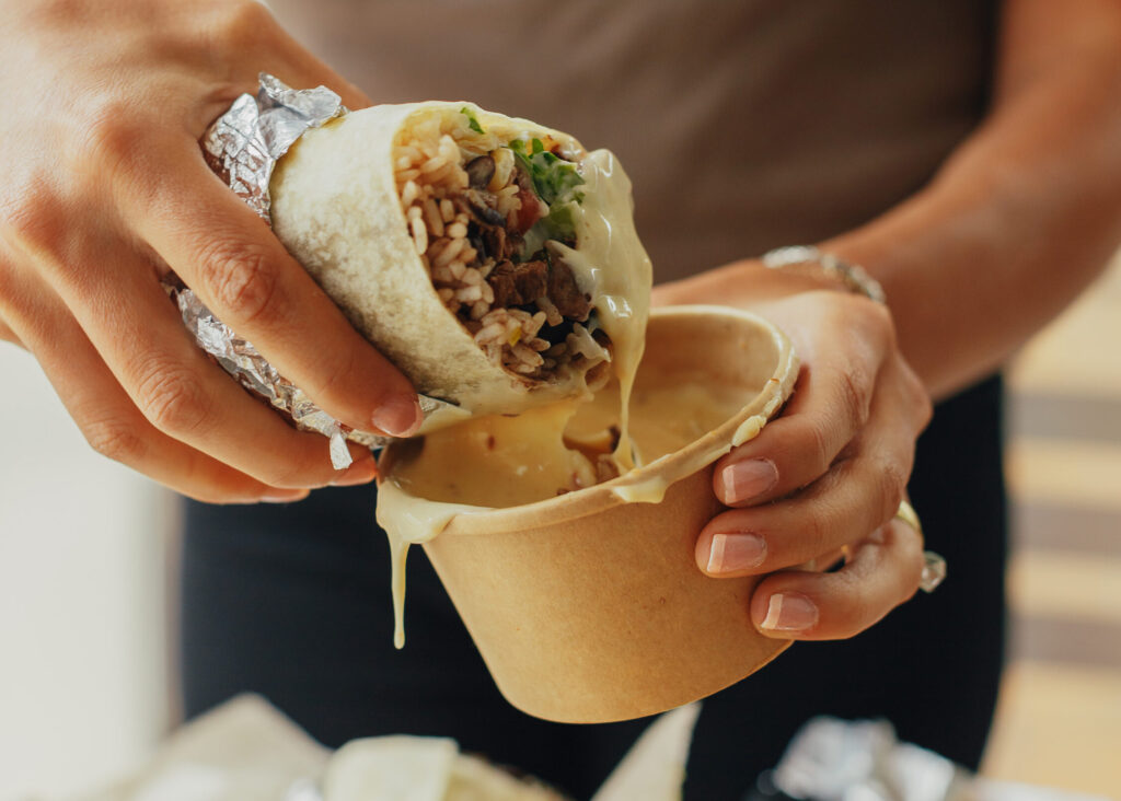 Burrito dipped in queso. Photo Credit: Mesa Grande Taqueria