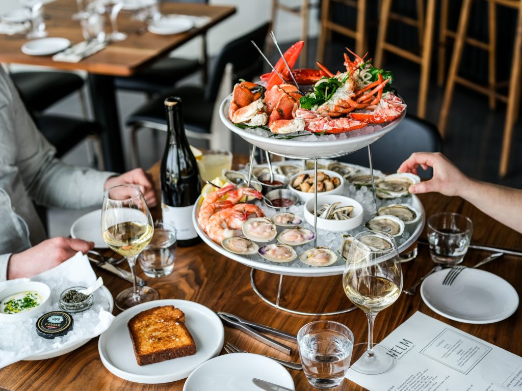 A two-tiered seafood tower with lobster, shrimp, and oysters on a restaurant table in Portland Maine.