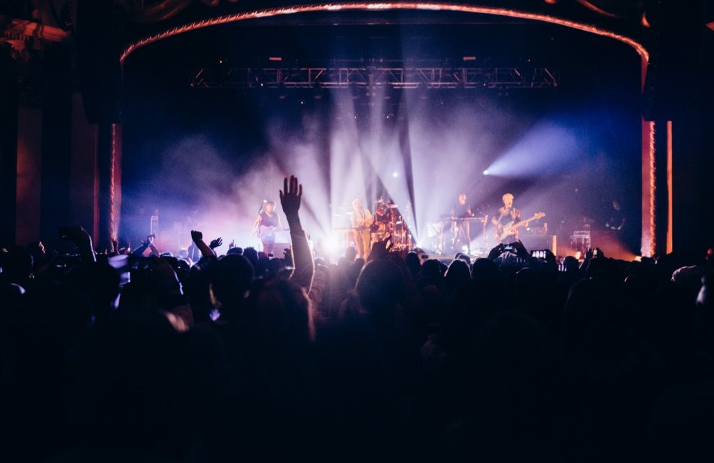 A crowd watches a band perform on a stage under bright spotlights in Portland Maine.