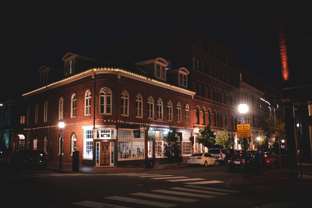 A historic brick building on a city street corner illuminated at night in Portland Maine.