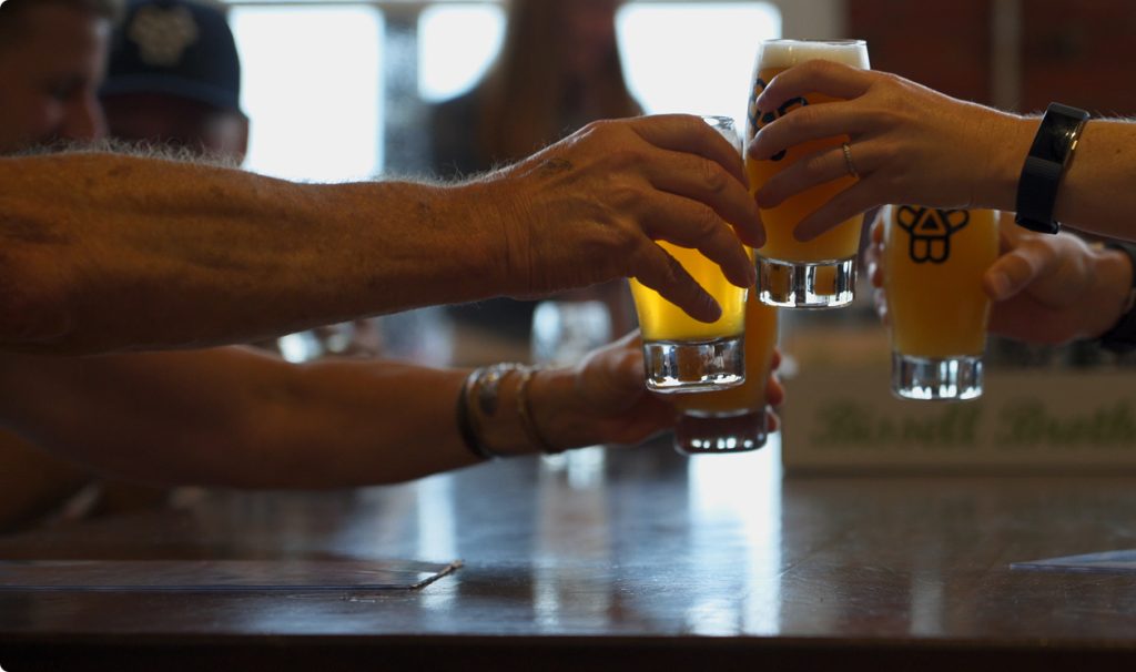 A group of people clinking glasses of beer together in a toast in Portland Maine.