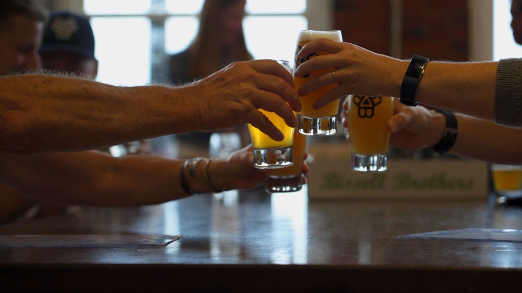 A group of people clinking glasses of beer together in a toast in Portland Maine.