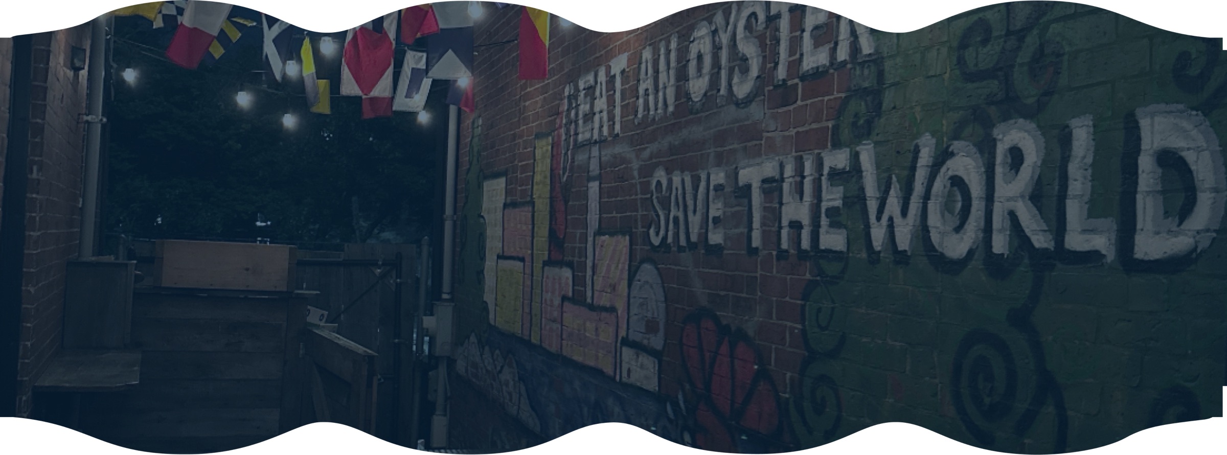 A brick wall with a mural reading Eat An Oyster Save The World in Portland Maine.