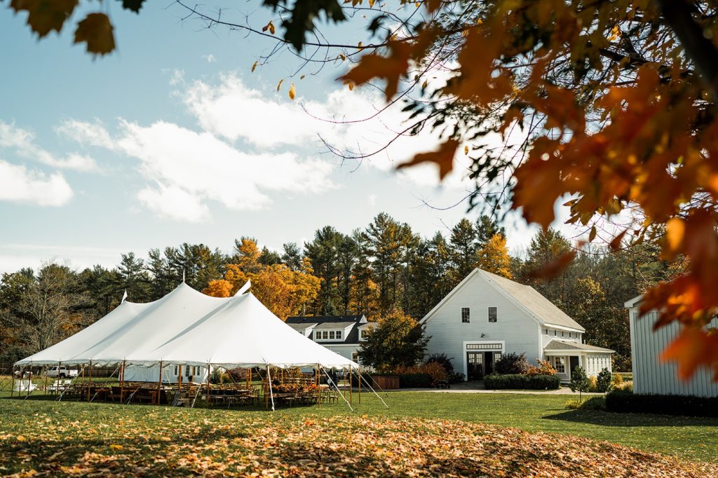 A large white event tent set up on a lawn near a white barn in Portland Maine.