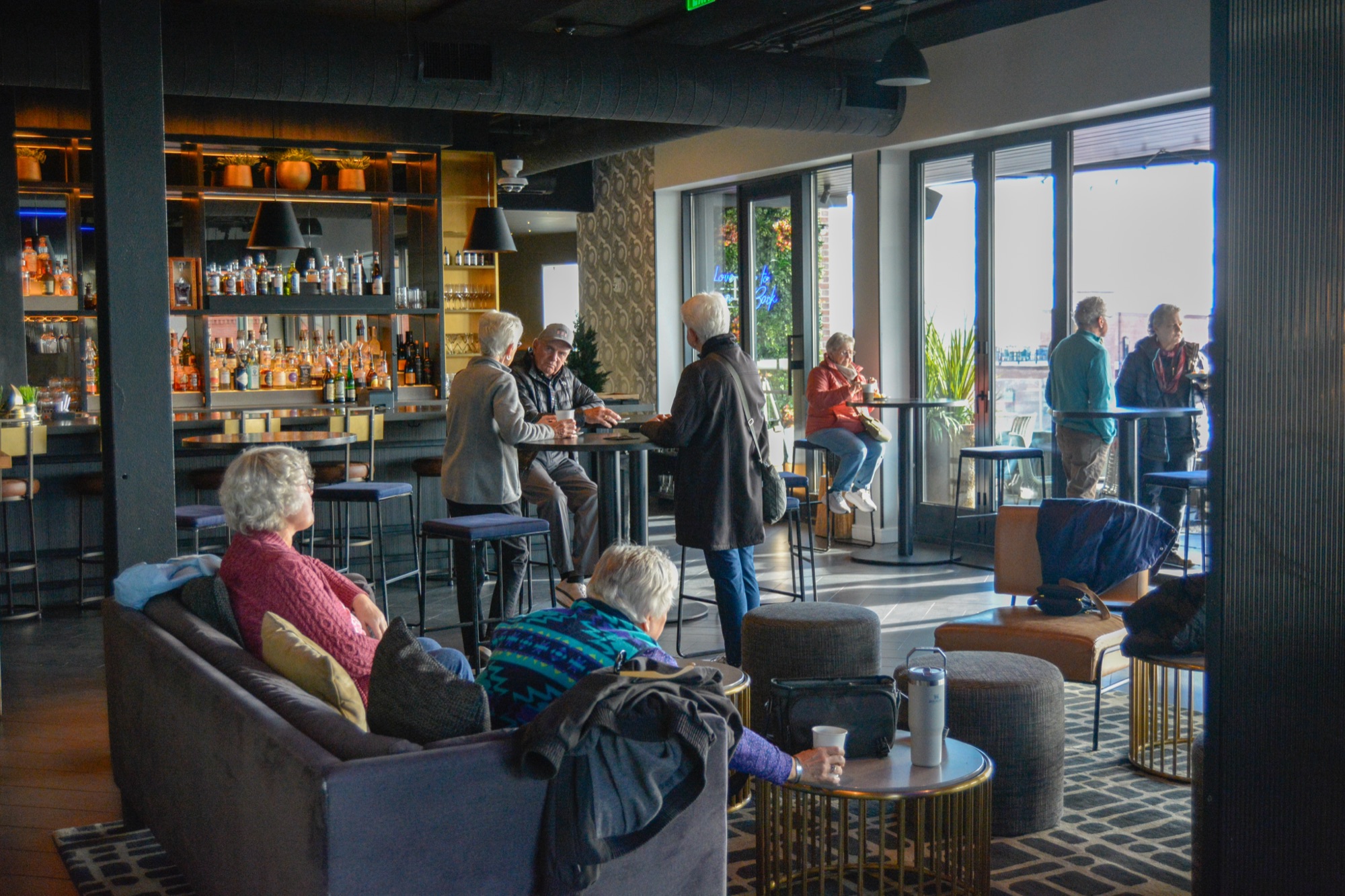 People relaxing and socializing in a modern, dimly lit lounge with a bar in Portland Maine.