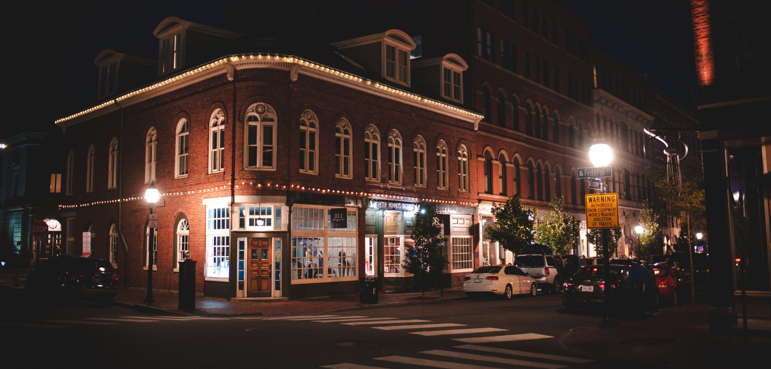A historic brick building on a street corner illuminated at night in Portland Maine.