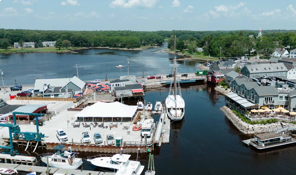 An aerial view of a harbor with boats, buildings, and a large white tent in Portland Maine.