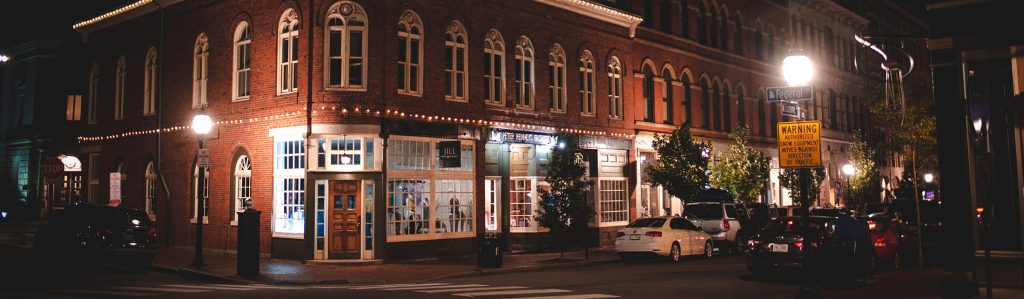 A historic brick building on a street corner illuminated at night in Portland Maine.