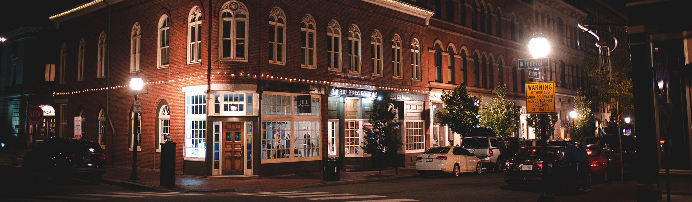 A historic brick building on a street corner illuminated at night in Portland Maine.