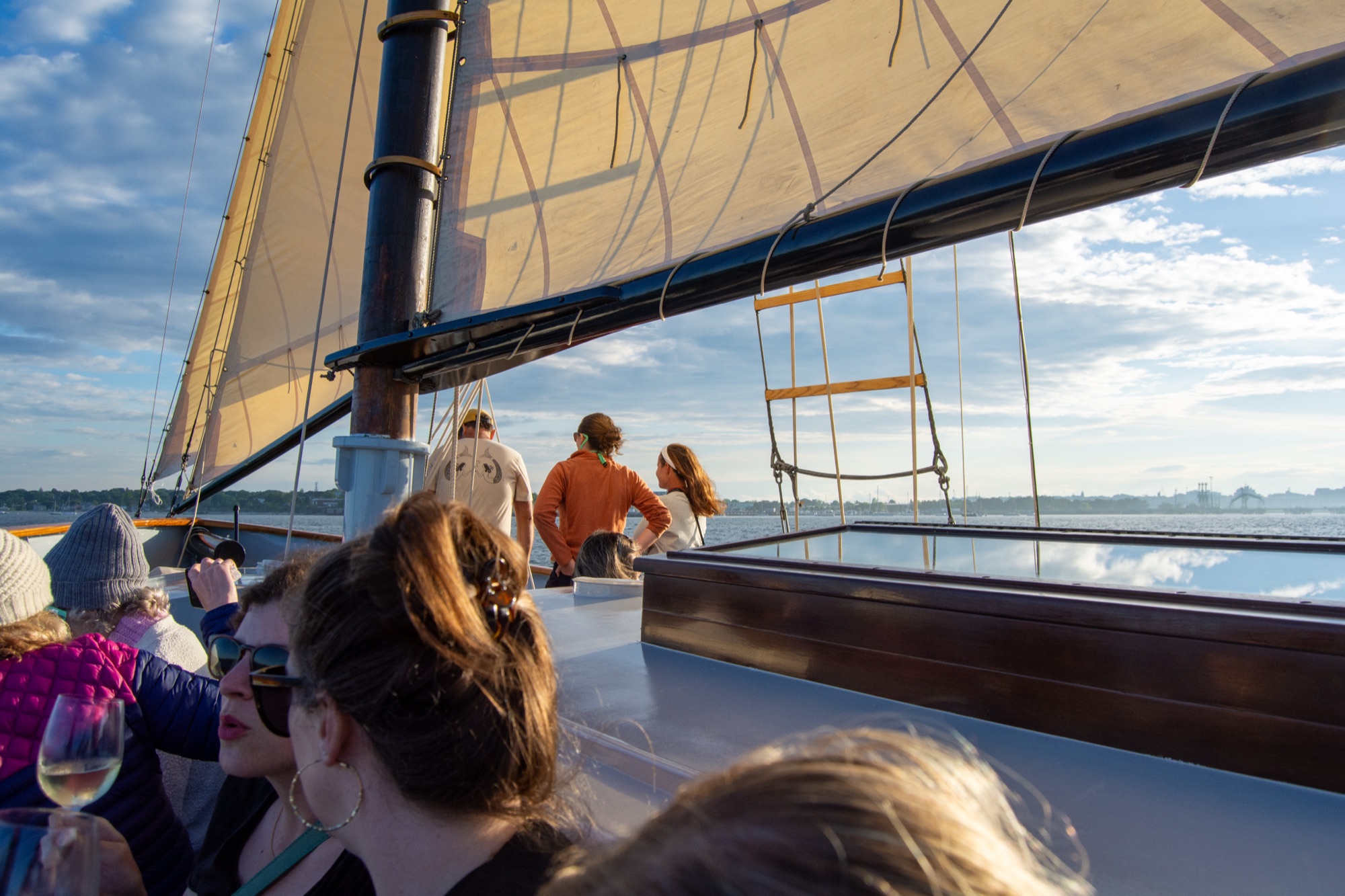 People relaxing on the deck of a sailboat during a sunny day in Portland Maine.