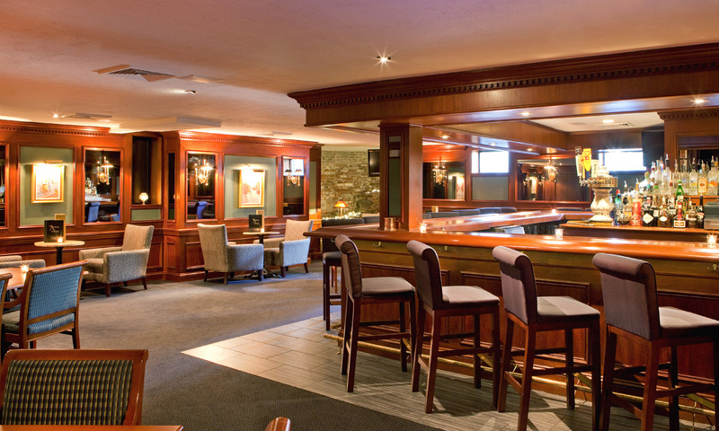 A dimly lit, elegant hotel bar with wooden paneling and comfortable seating in Portland Maine.